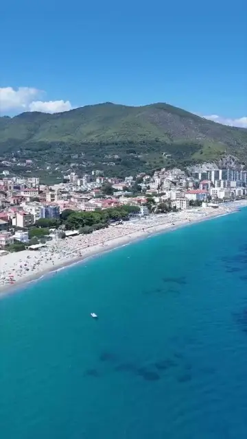 Spotorno dall'alto in verticale: la spiaggia, il paese e il monte dietro, acqua turchese in primo piano